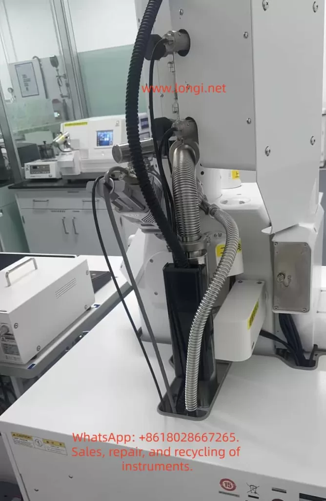Rear-side view of a JEOL JSM-IT700HR/LA scanning electron microscope showing vacuum hoses, metal bellows, cables, pump connections, and rear vacuum system components.