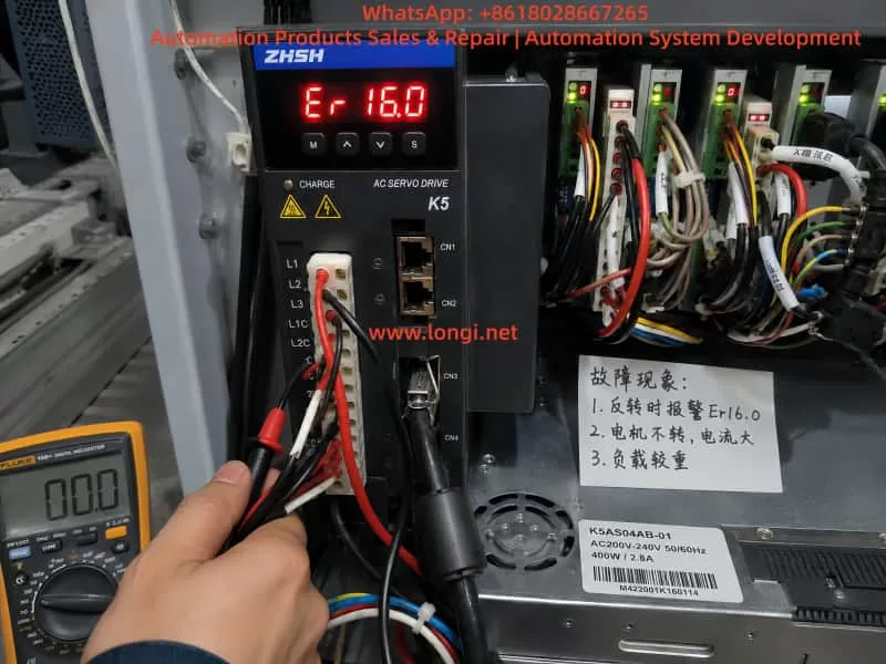 Zhishan K5 AC servo drive showing Er16.0 overload alarm while a technician performs electrical diagnostics inside an industrial automation control panel.
