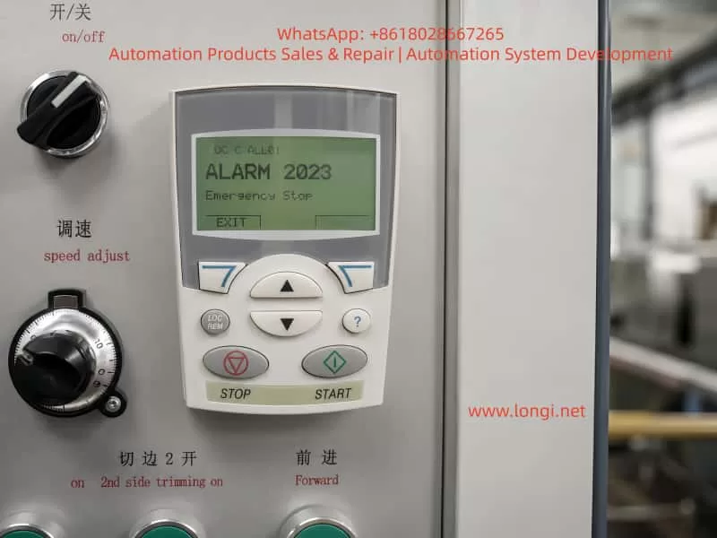 Close-up of an ABB ACS550 drive keypad displaying Alarm 2023 Emergency Stop on an industrial machine control panel.