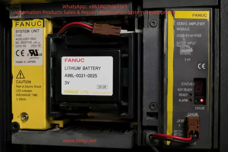 Close-up view of a FANUC CNC internal electronic module showing a lithium backup battery pack and servo amplifier components, with wiring connectors and labeled industrial control hardware inside a machine cabinet.