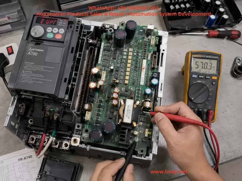 Technician diagnosing a Mitsubishi FR-A740 7.5kW inverter with E.UVT undervoltage alarm using a digital multimeter measuring 570V DC on the power/control board inside an open drive cabinet during industrial maintenance.